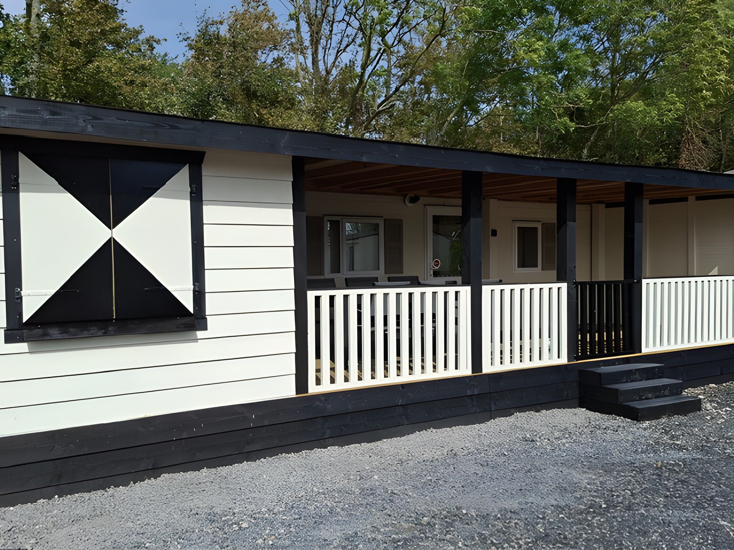 A single-story building with a covered porch and a black railing.