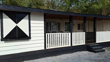 A single-story building with a covered porch and a black railing.
