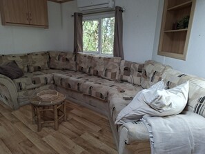 Zona d'estar acollidora amb un sofà, una taula rodona petita i una finestra amb cortines.