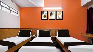 A hotel room with three single beds, a small table, a chair, and a wall-mounted TV. - Super Townhouse Hubli Bus Terminal (Hubli-Dharwad)