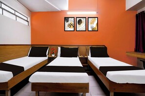 A hotel room with three single beds, a small table, a chair, and a wall-mounted TV. - Super Townhouse Hubli Bus Terminal (Hubli-Dharwad)