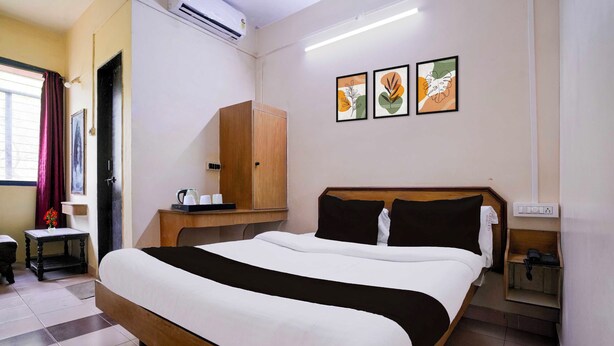 A hotel room with a bed, a wooden wardrobe, a small table with a kettle, and a wall-mounted phone. - Super Townhouse Hubli Bus Terminal (Hubli-Dharwad)