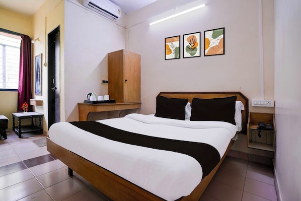 A hotel room with a bed, a wooden wardrobe, a small table with a kettle, and a wall-mounted phone. - Super Townhouse Hubli Bus Terminal (Hubli-Dharwad)