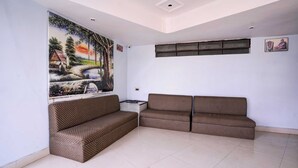 A living room with a large painting, a sofa set, and a ceiling with recessed lighting. - Super Townhouse Hubli Bus Terminal (Hubli-Dharwad)
