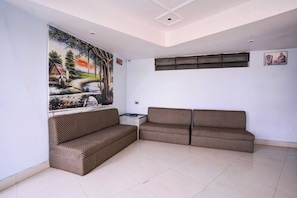A living room with a large painting, a sofa set, and a ceiling with recessed lighting. - Super Townhouse Hubli Bus Terminal (Hubli-Dharwad)