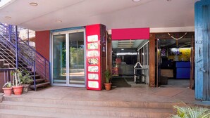 A hotel entrance with a staircase, a glass door, and a red vertical sign with images of food. - Super Townhouse Hubli Bus Terminal (Hubli-Dharwad)