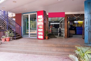 A hotel entrance with a staircase, a glass door, and a red vertical sign with images of food. - Super Townhouse Hubli Bus Terminal (Hubli-Dharwad)