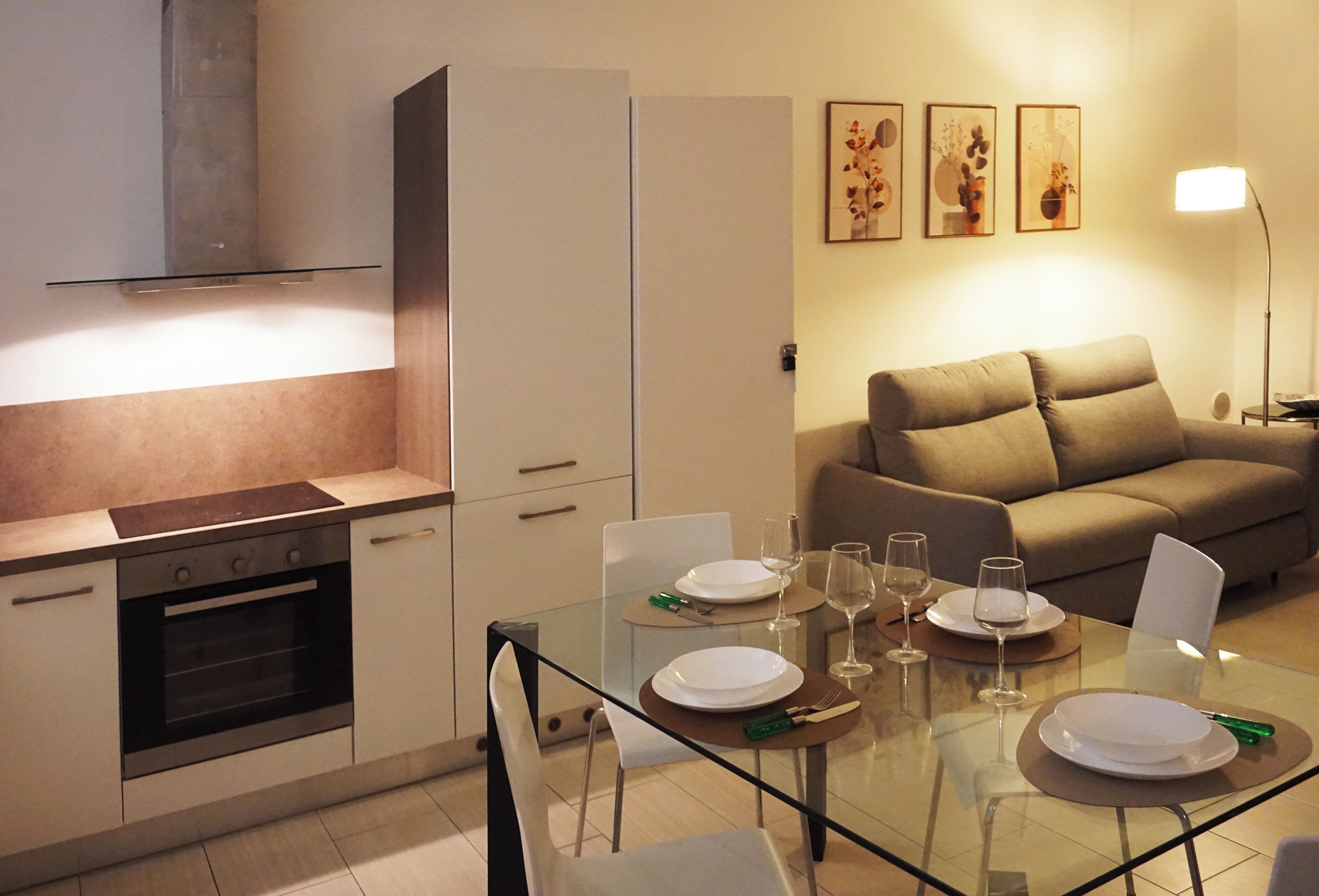 Eine moderne Küche mit Essbereich, einer Couch und Wandbildern.
