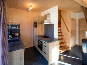 A compact kitchen with wooden walls, a built-in oven, and a countertop. - One-bedroom Cabin (Sankt Georgen am Kreischberg)
