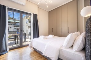 Ein modernes Schlafzimmer mit einem großen Bett, einer Schiebetür zum Balkon und Blick auf die Stadt.
