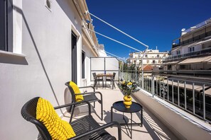 A balcony with outdoor furniture, a small table, and a potted plant. - FiftySeven Athens - Two Ways Outside, 2BR | 302 (Athina)