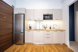 Cozinha moderna com geladeira de aço inoxidável, micro-ondas Bosch e bancadas de madeira.