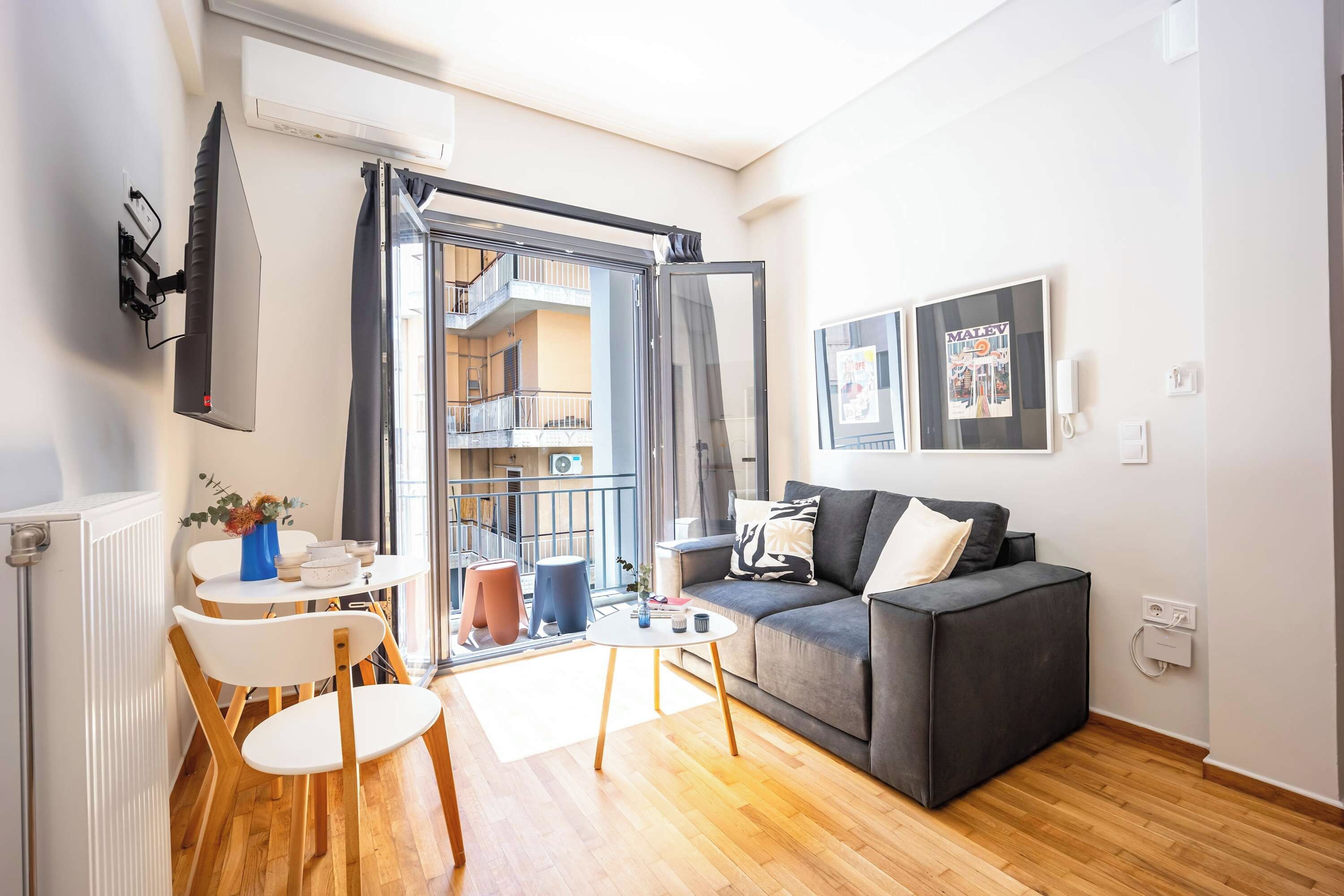 Un salon moderne avec un canapé gris, une table basse blanche et un coin repas comprenant une petite table et des chaises.