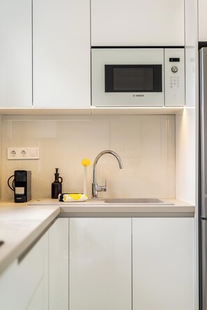 A modern kitchen with white cabinets, a Bosch microwave, a coffee maker, and a sink. - FiftySeven Athens - 2BR, Terrace & Balcony | 301 (Athina)