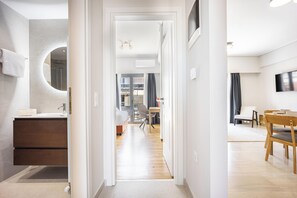 A modern hotel room with a bathroom, a dining area, and a living space. - FiftySeven Athens - 2BR, Terrace & Balcony | 301 (Athina)