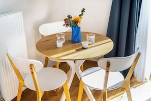 Ein runder Holztisch mit zwei weißen Stühlen, einer blauen Vase mit Blumen und zwei Gläsern.