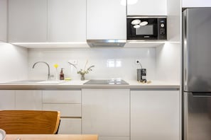 A modern kitchen with white cabinetry, a stainless steel refrigerator, a Bosch microwave, and a coffee machine. - FiftySeven Athens - Spacious 2BR, Terrace | 103 (Athina)