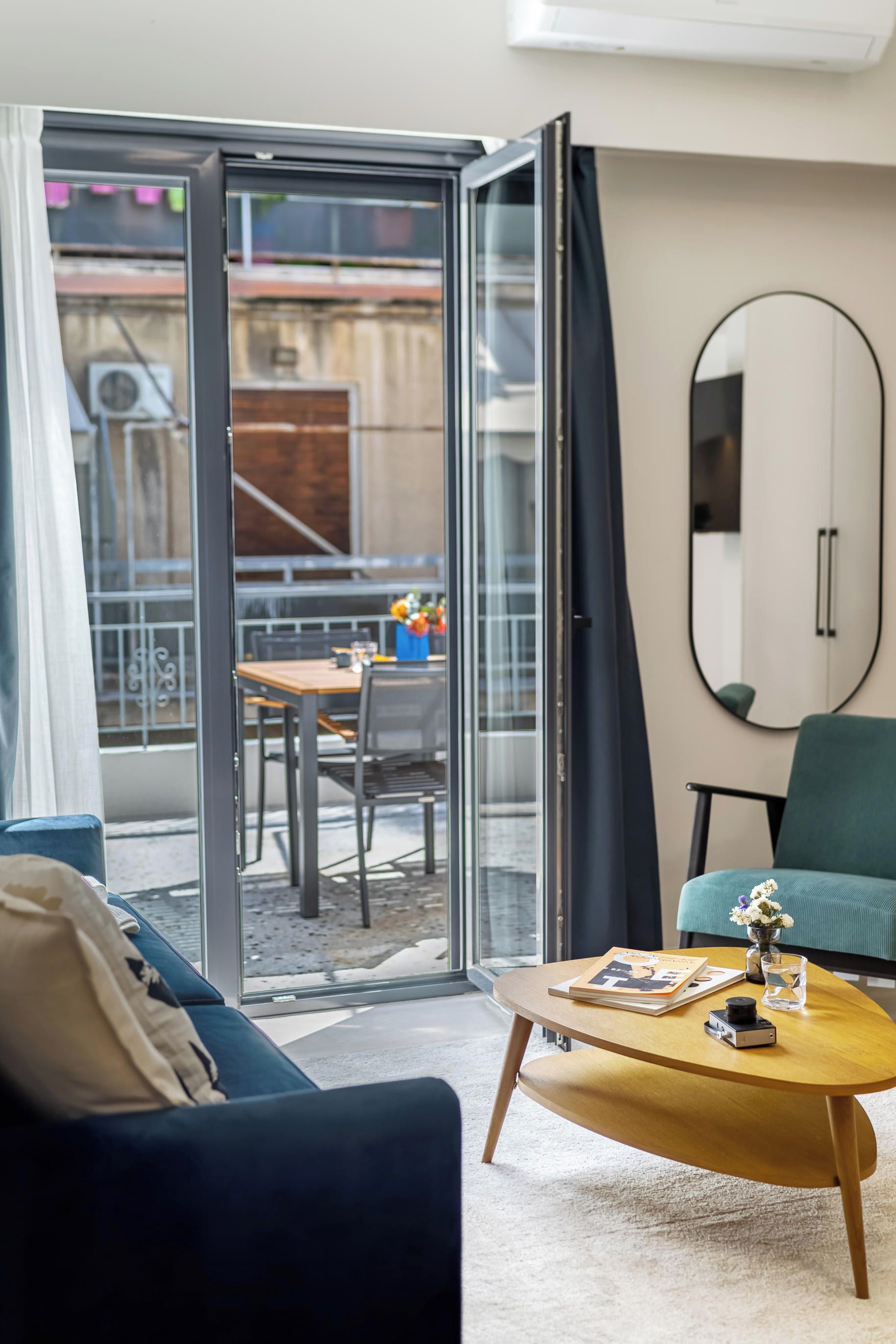 Un salon moderne avec un canapé, une table basse et un coin repas visible à travers une porte vitrée.
