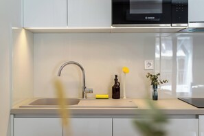 A modern kitchen with a Bosch microwave, a stainless steel sink, and a vase with a plant. - FiftySeven Athens - Towards Lycabettus | 203 (Athina)