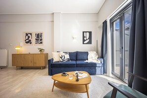 A modern living room with a blue sofa, wooden coffee table, and abstract art on the wall. - FiftySeven Athens - Towards Lycabettus | 203 (Athina)