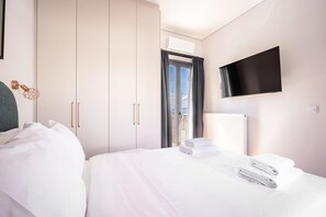 Ein Hotelzimmer mit Bett, Flachbildfernseher an der Wand und einem Fenster mit Vorhängen.