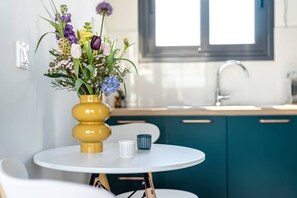 Eine moderne Küche mit türkisblauen Schränken, einer weißen Spüle und einem gelben Blumenvasen auf einem weißen Tisch.