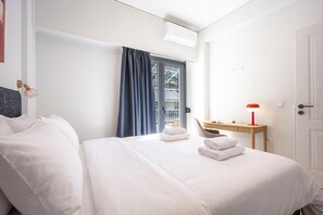 A hotel room with a bed, a desk, a chair, a window with curtains, and a door. - FiftySeven Athens - Lycabettus Glimpse | 202 (Athina)