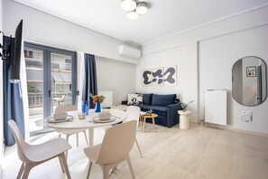 A modern living room with a dining area, a sofa, and a large window. - FiftySeven Athens - Lycabettus Glimpse | 202 (Athina)