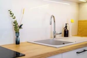 A modern kitchen with a stainless steel sink, a wooden countertop, and a vase with a plant. - FiftySeven Athens - Off the Street, Balcony | 204 (Athina)