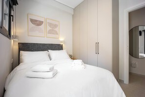 A neatly made bed with white linens and towels, a headboard with a textured pattern, and two framed artworks on the wall. - FiftySeven Athens - Off the Street, Balcony | 204 (Athina)