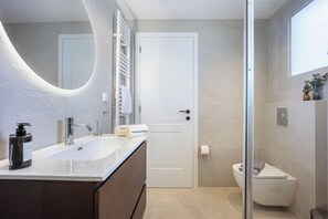 Ein modernes Badezimmer mit Waschbecken, Spiegel, Handtuchhalter und Toilette.