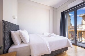 Ein Hotelzimmer mit Bett, Kissen, einem Nachttisch und Blick durch ein großes Fenster.