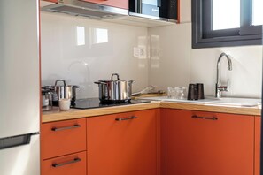 A modern kitchen with a microwave, stove, and sink. - FiftySeven Athens - Acropolis View Terrace | 501 (Athina)