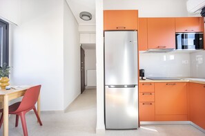 A modern kitchen with a stainless steel refrigerator, an orange cabinet, and a Bosch microwave. - FiftySeven Athens - Acropolis View Terrace | 501 (Athina)