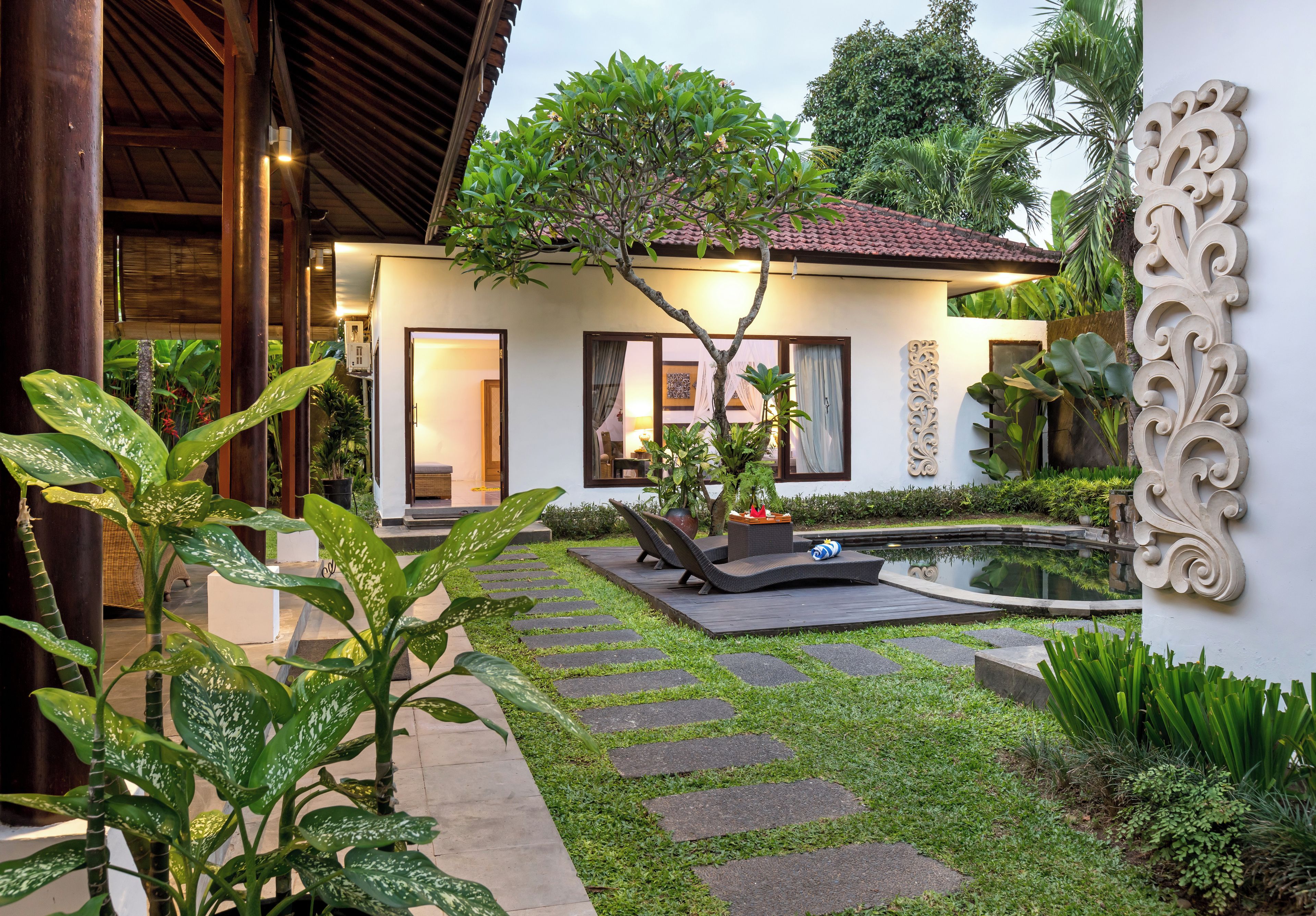 Una casa moderna con jardín, piscina y un muro decorativo.