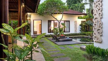 Una casa moderna con jardín, piscina y un muro decorativo.