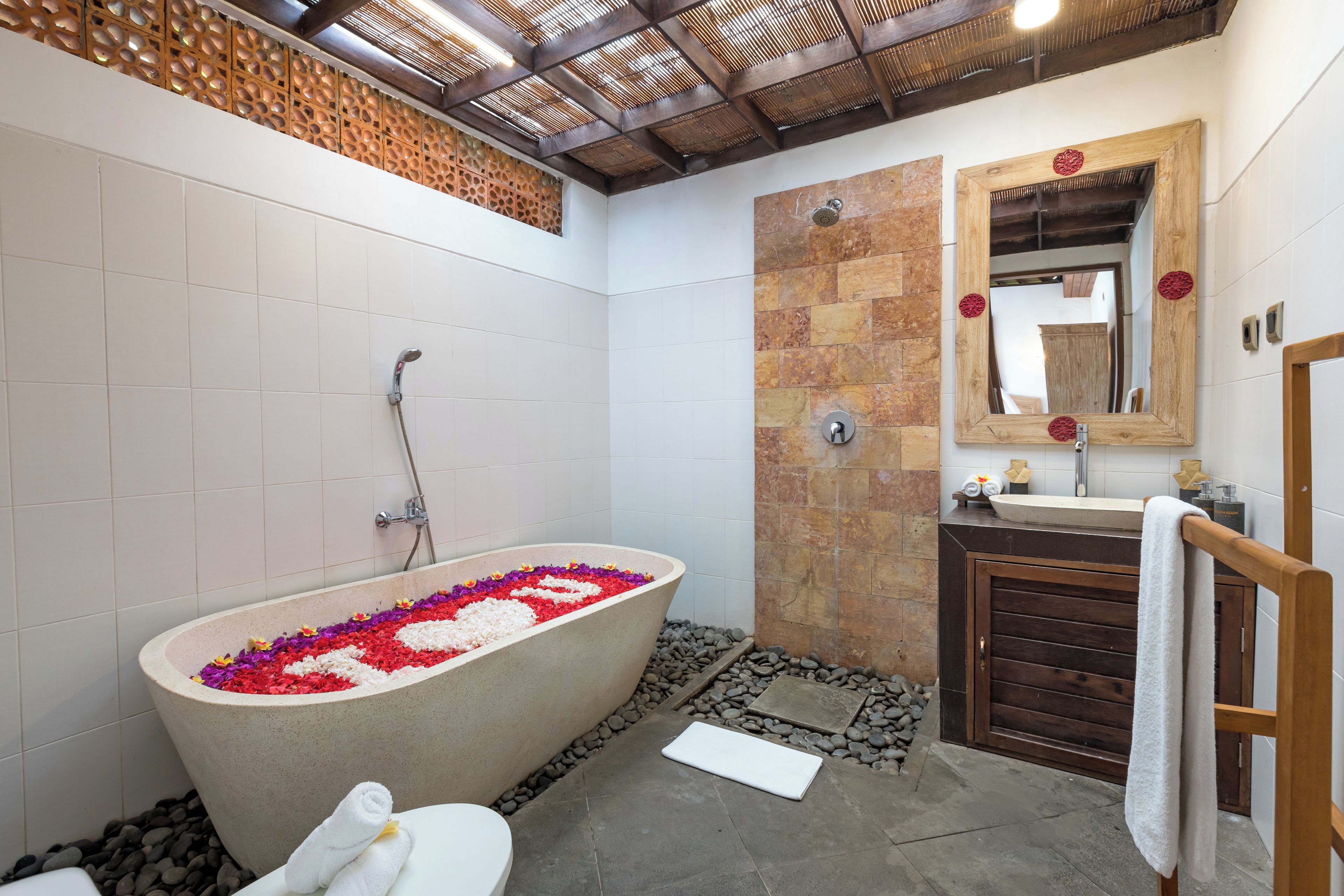 Un baño con una bañera independiente, un tocador de madera y un espejo grande.