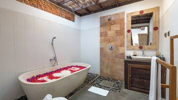 Un baño con una bañera independiente, un tocador de madera y un espejo grande.