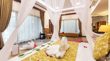 A hotel room with a bed, curtains, a chair, a bedside table, and a mirror.