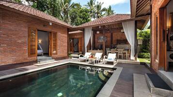 A poolside area with a clear pool, wooden deck, and lounge chairs.