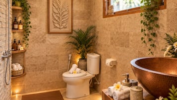 A bathroom with a wooden floor, a large copper sink, a toilet, and a shower area.