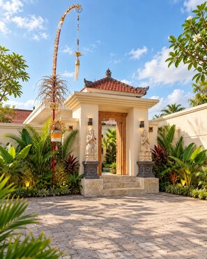 Un templo tradicional con techo de tejas, estatuas y un jardín bien cuidado.