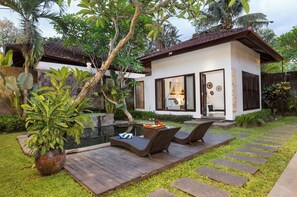 Una casa moderna con piscina, zona de estar exterior y exuberante vegetación.