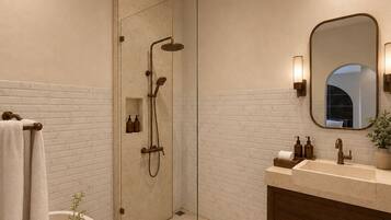 Un baño moderno con ducha acristalada, bañera independiente, tocador con lavabo y espejo.