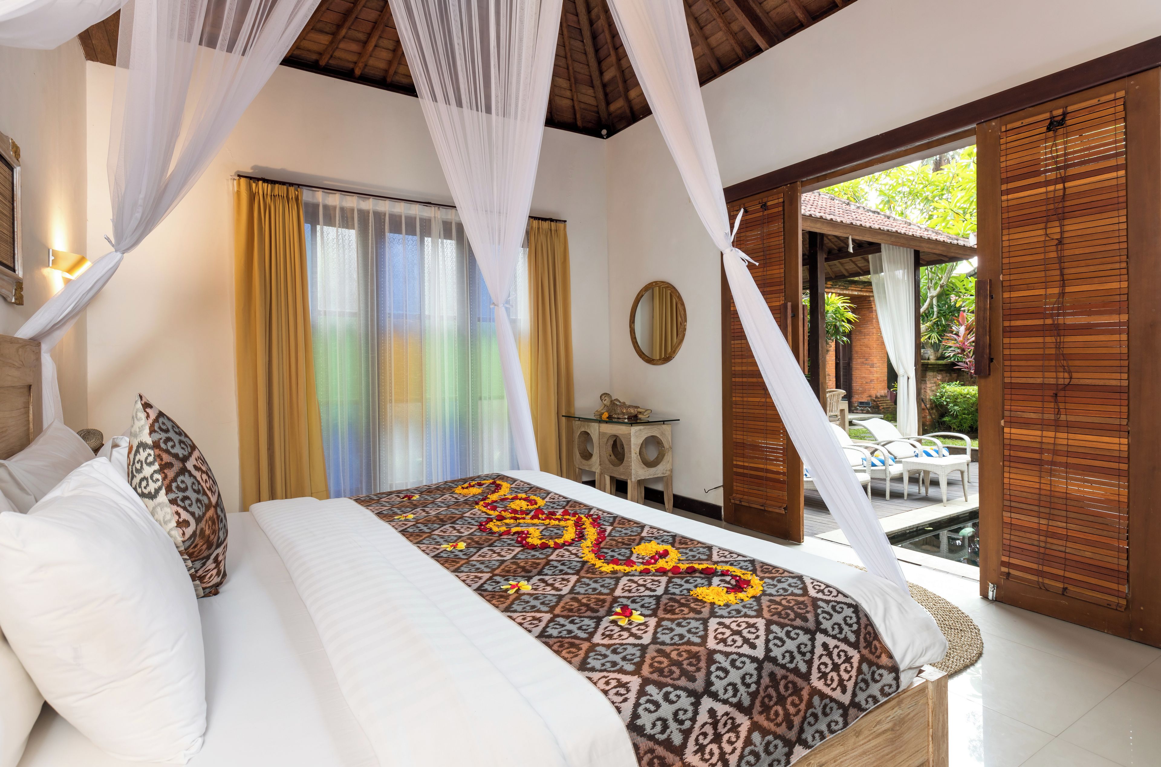 Un dormitorio con cama, mesita de noche, ventana con cortinas y vistas al exterior.