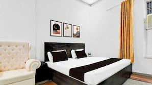 A bedroom with a bed, a sofa, and a window with curtains. - Townhouse Vrindavan Yojna Lucknow (Lucknow)
