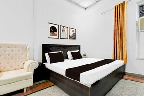 Quarto com cama, sofá e janela com cortinas.