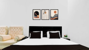 A bedroom with a bed, a chair, and three framed artworks on the wall. - Townhouse Vrindavan Yojna Lucknow (Lucknow)