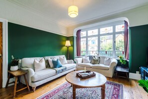 Ein Wohnzimmer mit einem weißen Sofa, einem runden Couchtisch und einem gemusterten Teppich.
