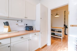 Eine moderne Küche mit weißen Schränken, einer Holz Arbeitsplatte, einem Toaster und einem Messerblock.